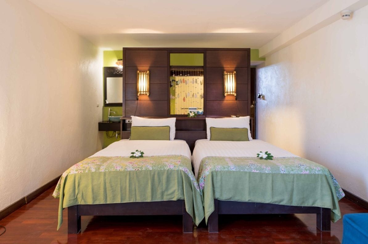 A double room with two beds, a large mirror, and wall-mounted lights.