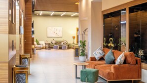 Un vestíbulo moderno con techo de madera, un área de estar con sofá y sillones, y un ventanal con adornos decorativos.