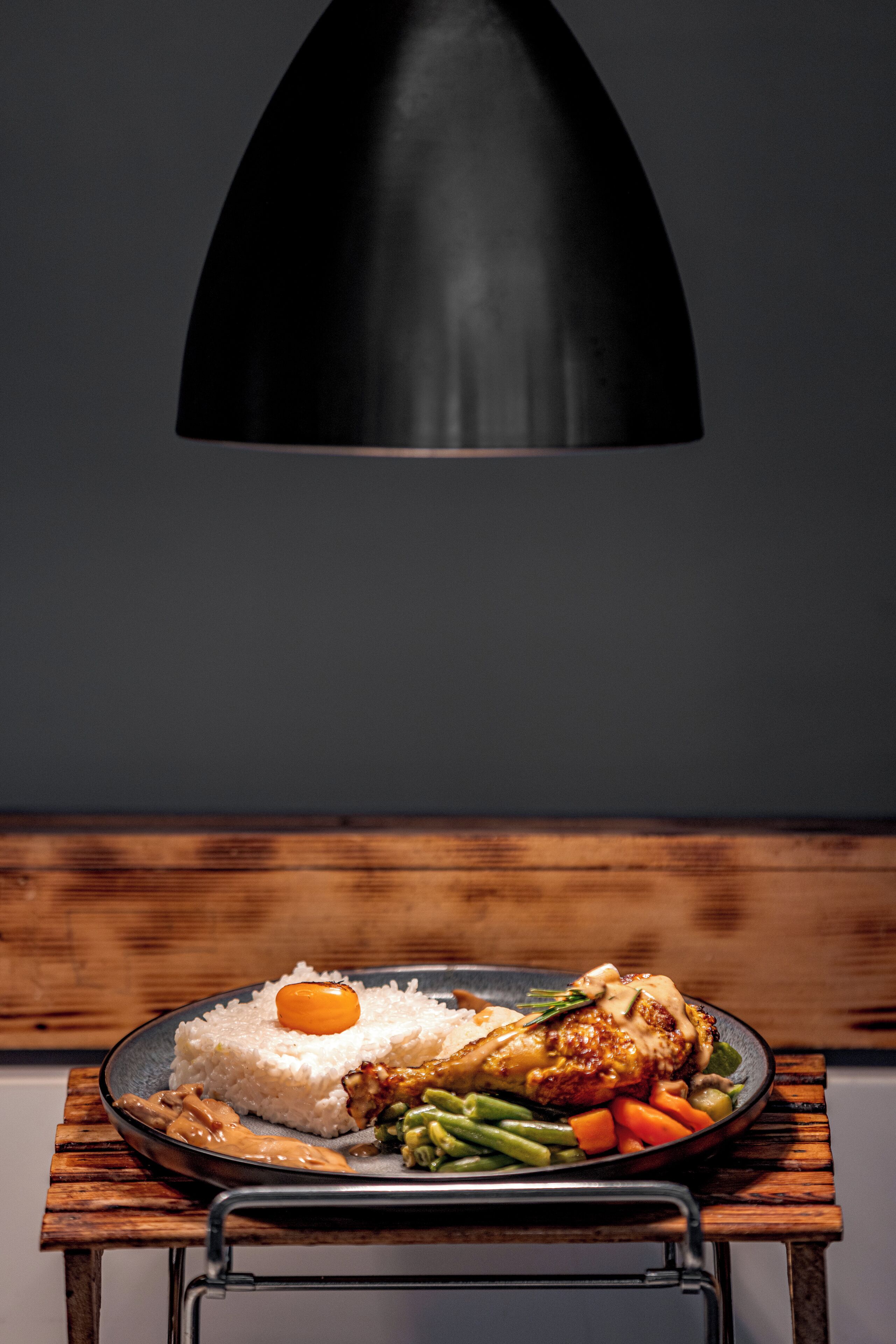 A plate of food on a table with a black lamp above.