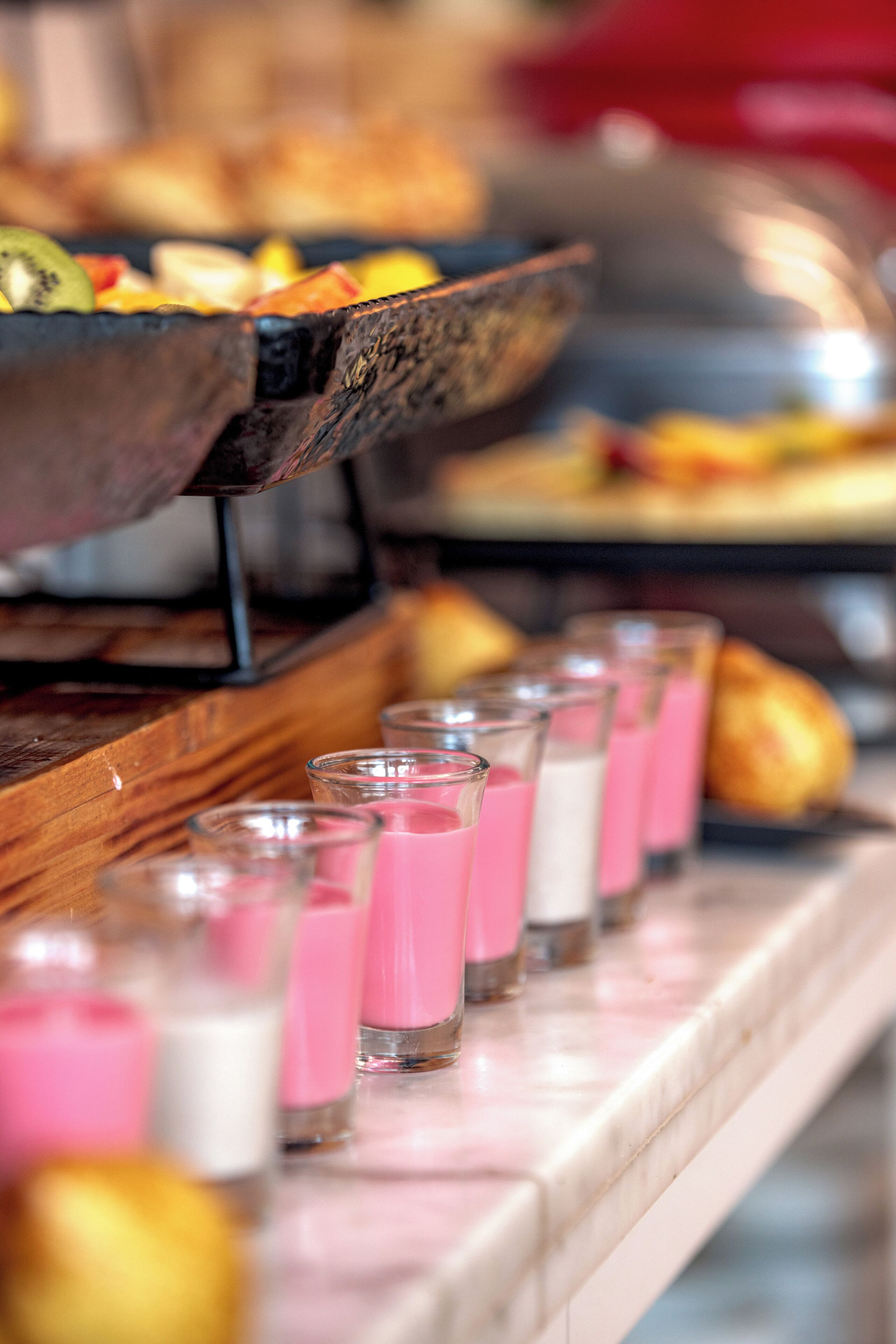 Buffet amb diferents aliments i begudes roses en vasos.