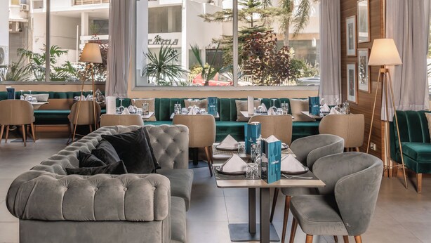 Un interior moderno con zona de comedor, sofás y un ventanal que ofrece vistas al exterior.