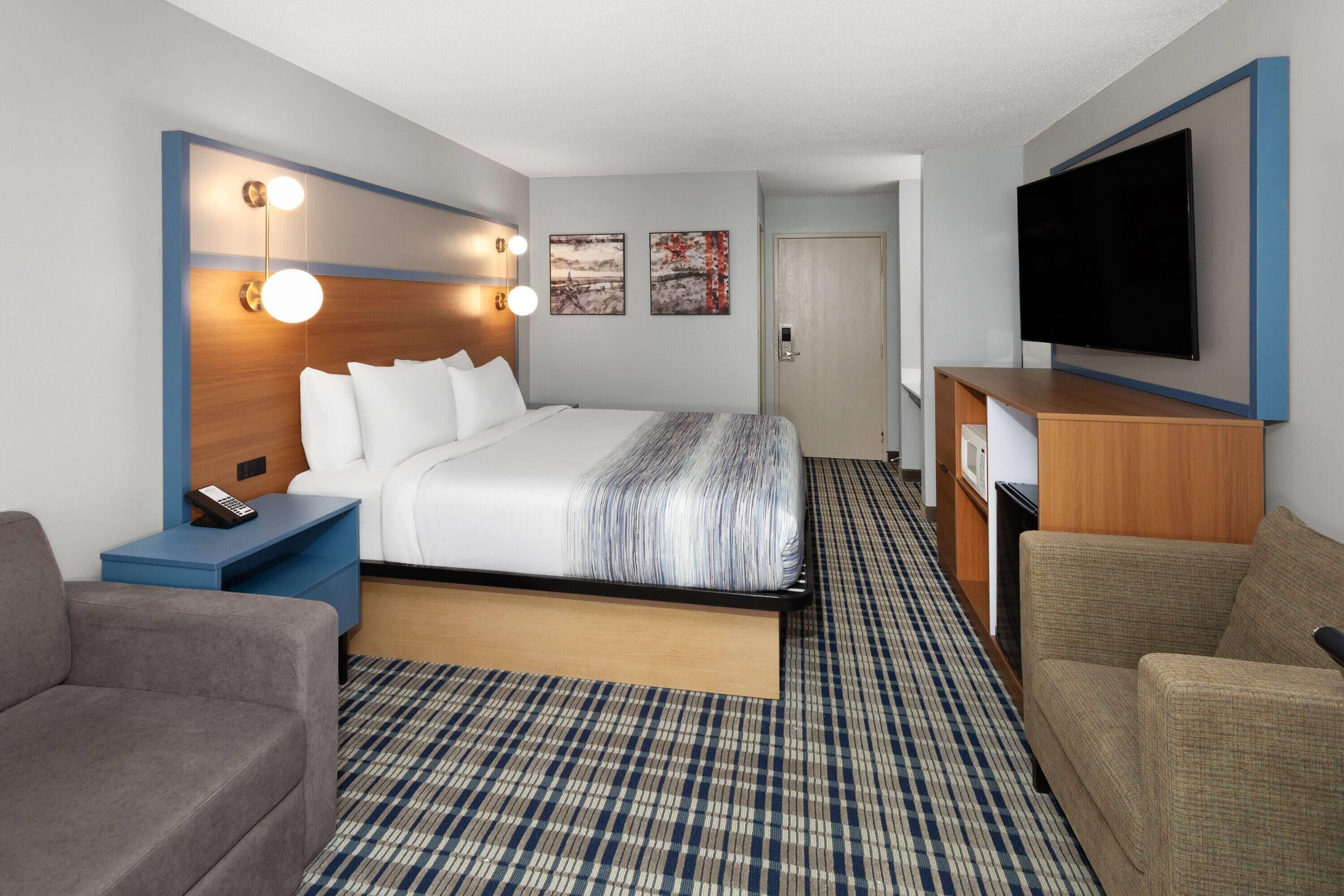 Una habitación de hotel con cama, mesita de noche, televisor y un sofá.