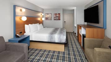 Una habitación de hotel con cama, mesita de noche, televisor y un sofá.