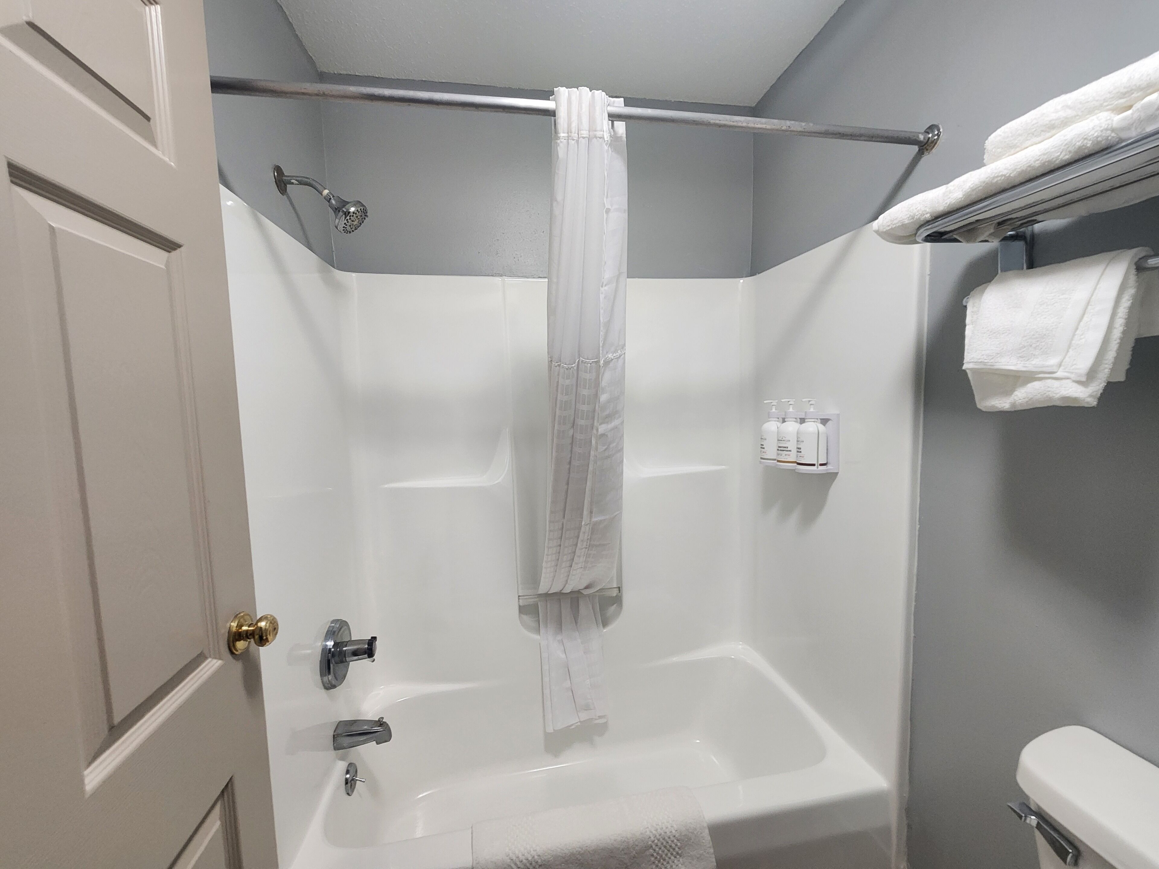 A bathroom with a shower, a bathtub, a toilet, and a towel rack.