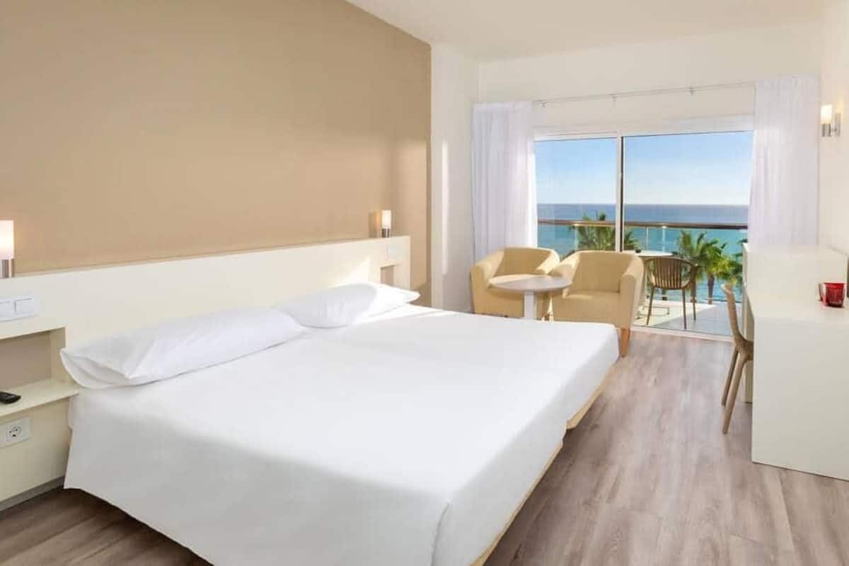 Une chambre d’hôtel avec un grand lit, un bureau, une chaise et un téléviseur.