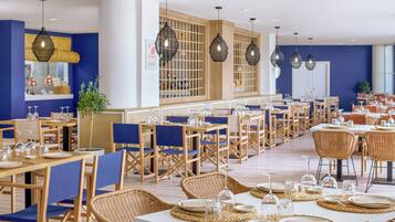Un restaurante con varias mesas y sillas, algunas con individuales tejidos y otras con manteles blancos.