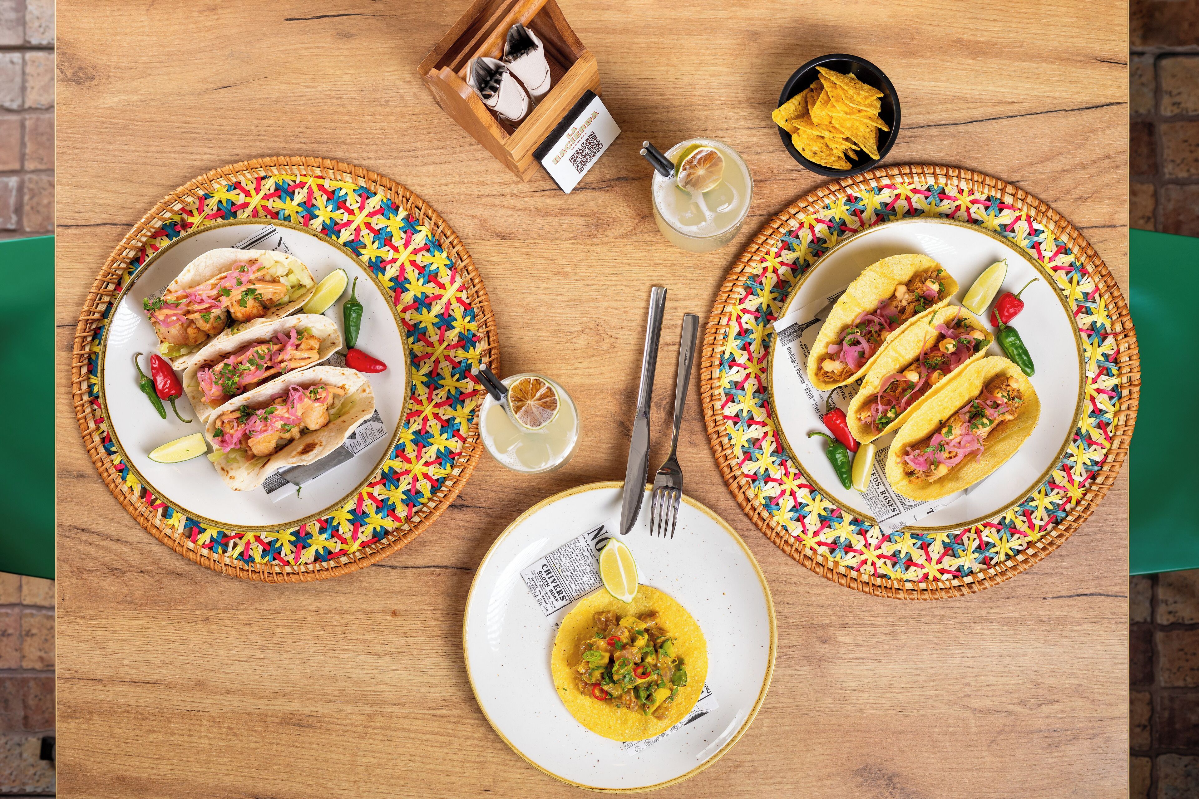 Una mesa con dos platos de tacos, un plato de polenta y un cuenco pequeño de totopos.