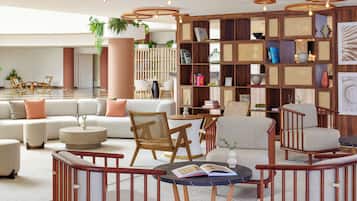Una sala de estar moderna con un sofá seccional, una mesa de centro redonda y una estantería llena de libros y objetos decorativos.
