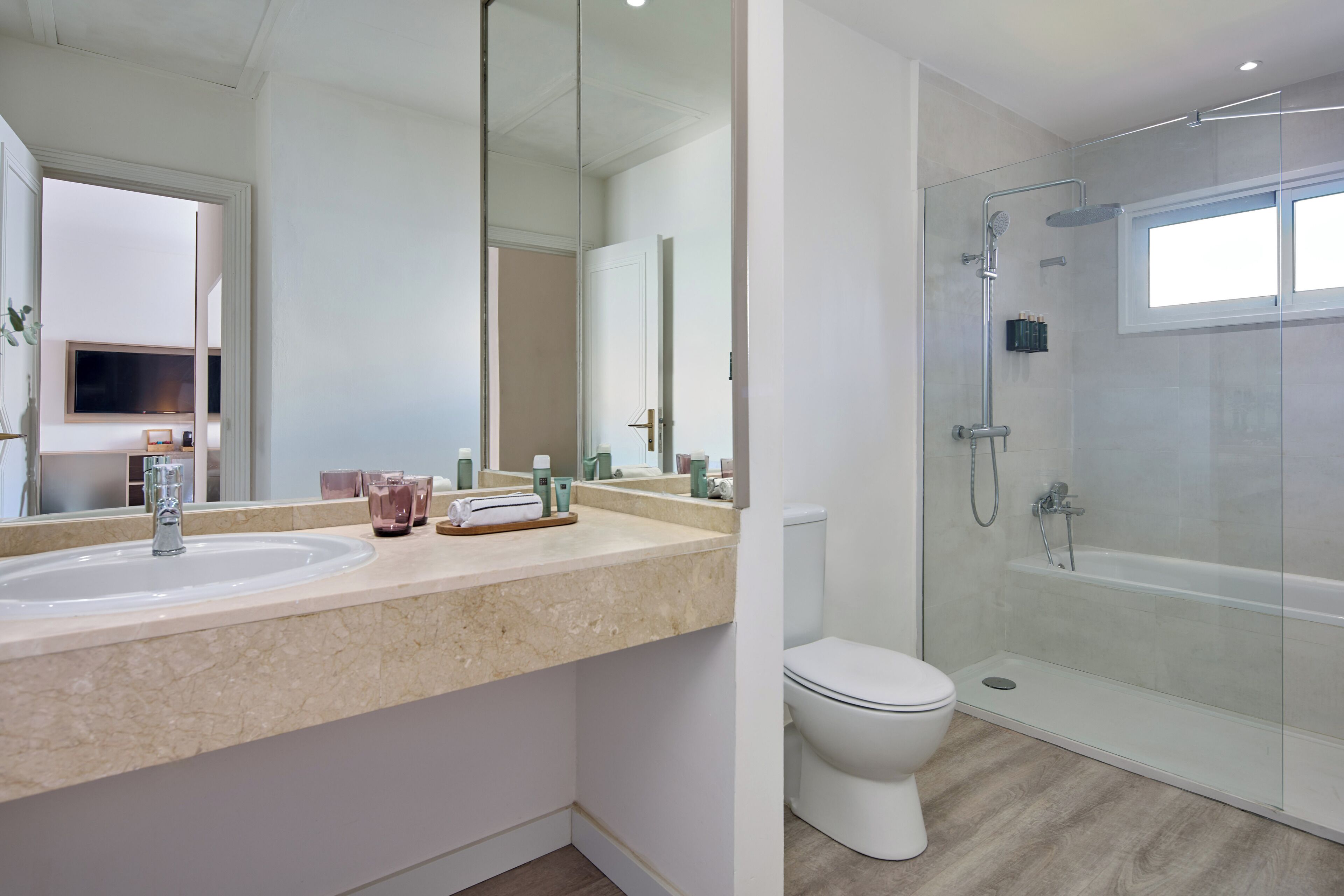 Un baño moderno con ducha de vidrio, tocador doble y un inodoro.