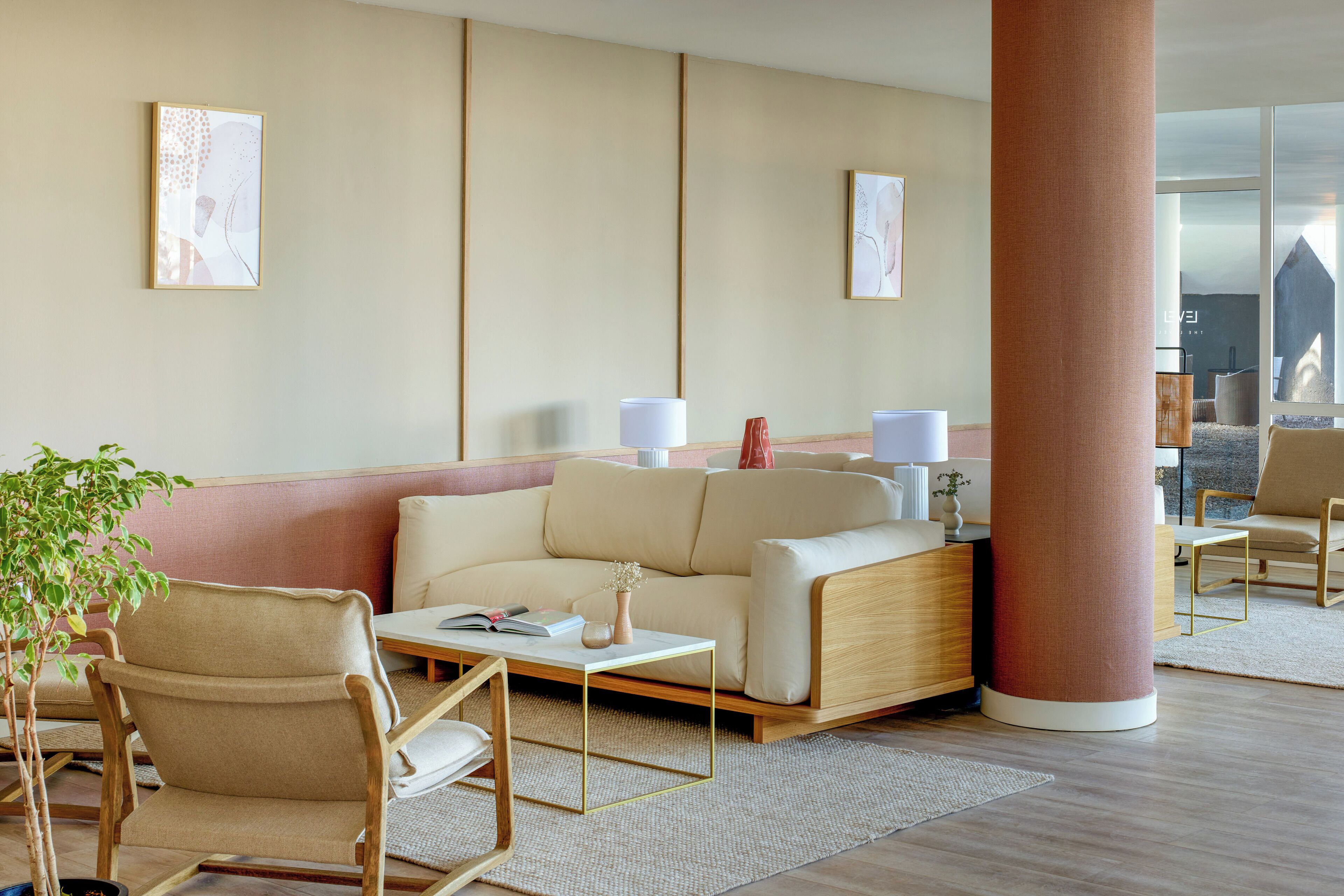 Un moderno vestíbulo de hotel con un sofá, sillas, una mesa de centro y obras de arte en las paredes.