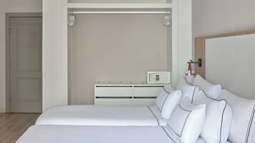 A modern hotel room with a large bed, a bedside table with a lamp, and a wardrobe.
