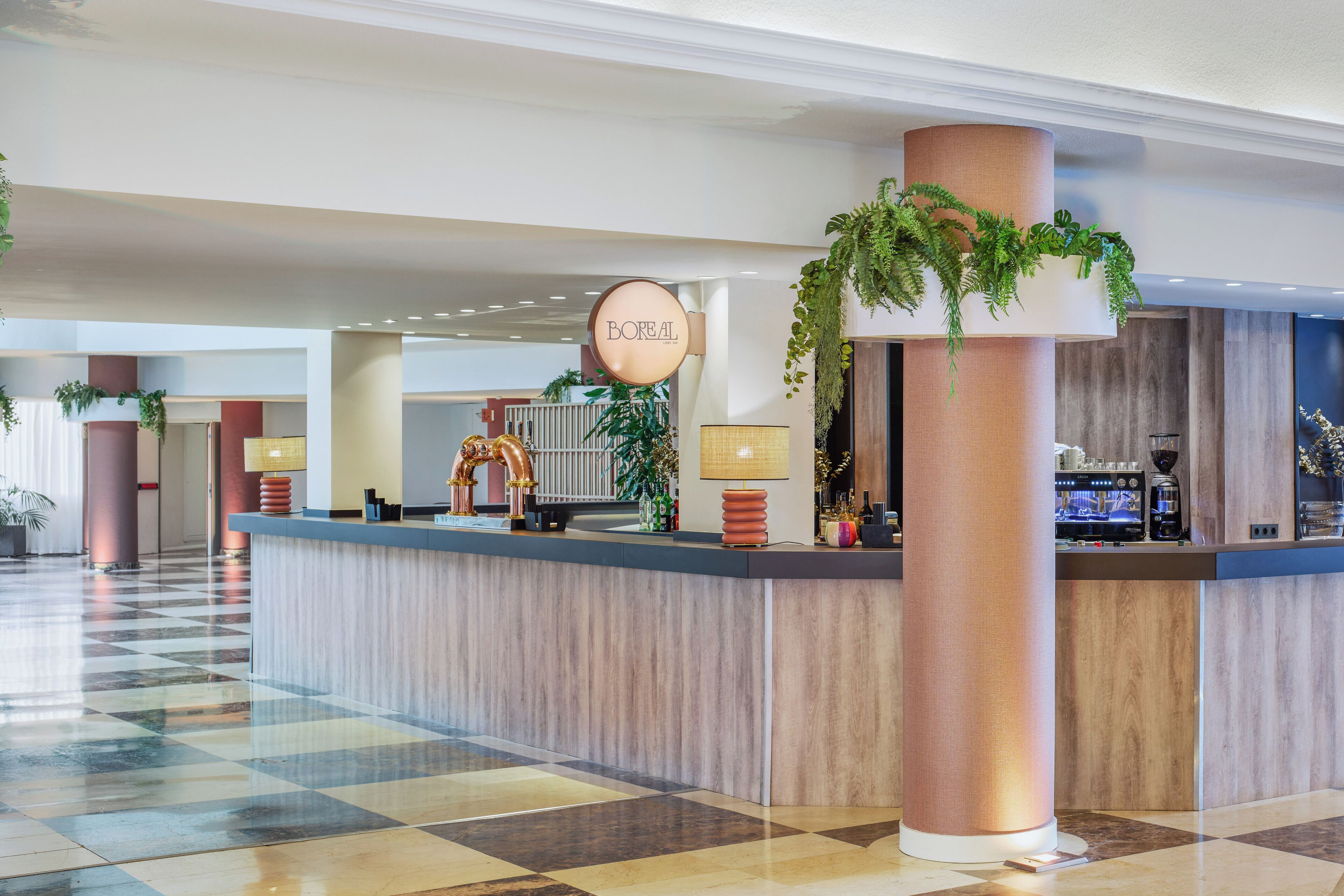 Een hotel lobby met een receptiebalie, een grote kolom met beplanting en een incheckbalie.