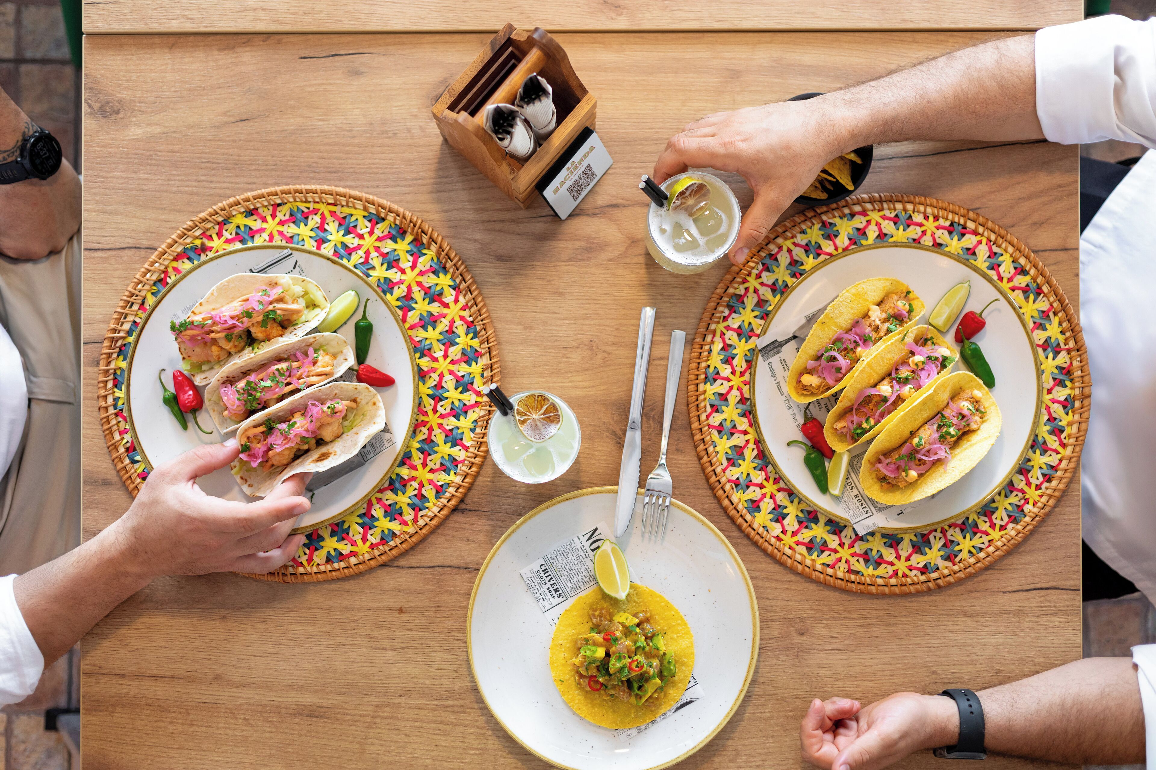 Ein Holztisch mit zwei Tacos und einer Schüssel Suppe.