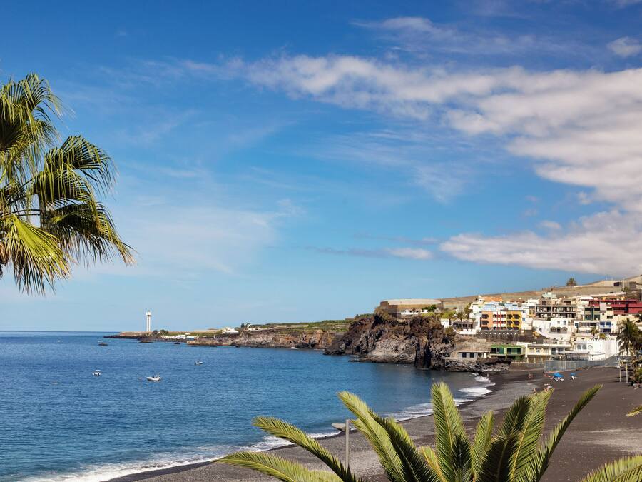 Un pueblo costero con playa, edificios y un faro.