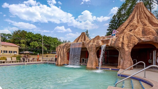 Una piscina con cascadas y un área de descanso con sillas y sombrillas.