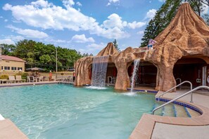 A pool with waterfalls and a lounge area with chairs and umbrellas. - Atlantis Family Waterpark Hotel, an Ascend Collection Hotel (Wisconsin Dells)