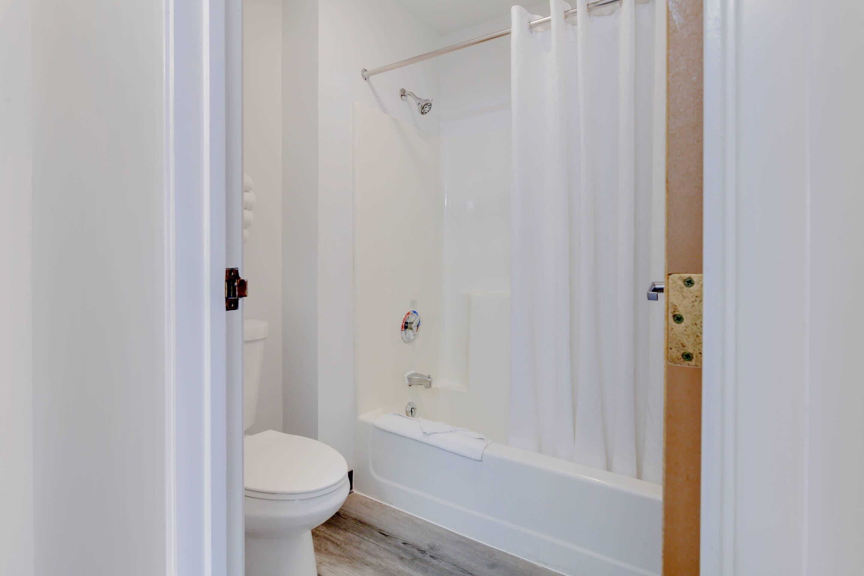 Een badkamer met toilet, bad en douchegordijn.