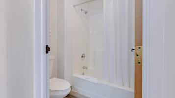 Een badkamer met toilet, bad en douchegordijn.