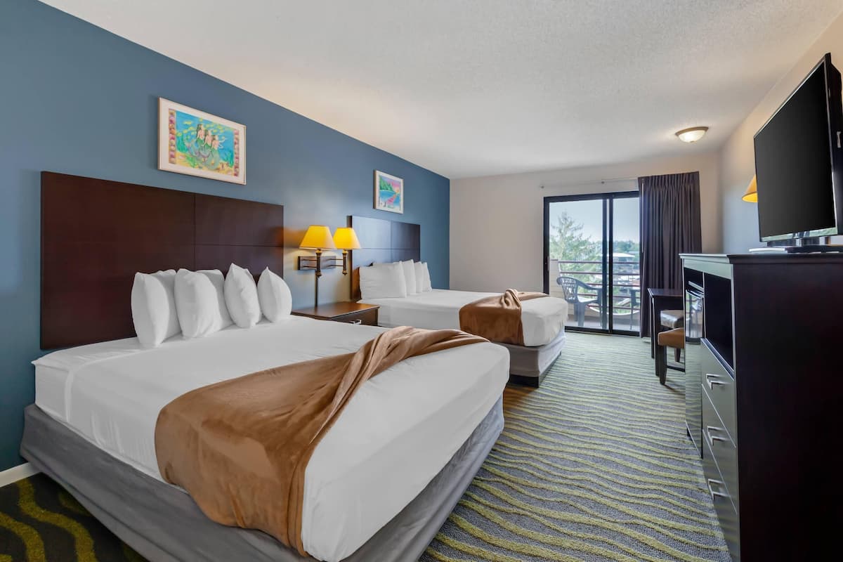 A hotel room with two beds, a television, a desk, and a balcony with a view.