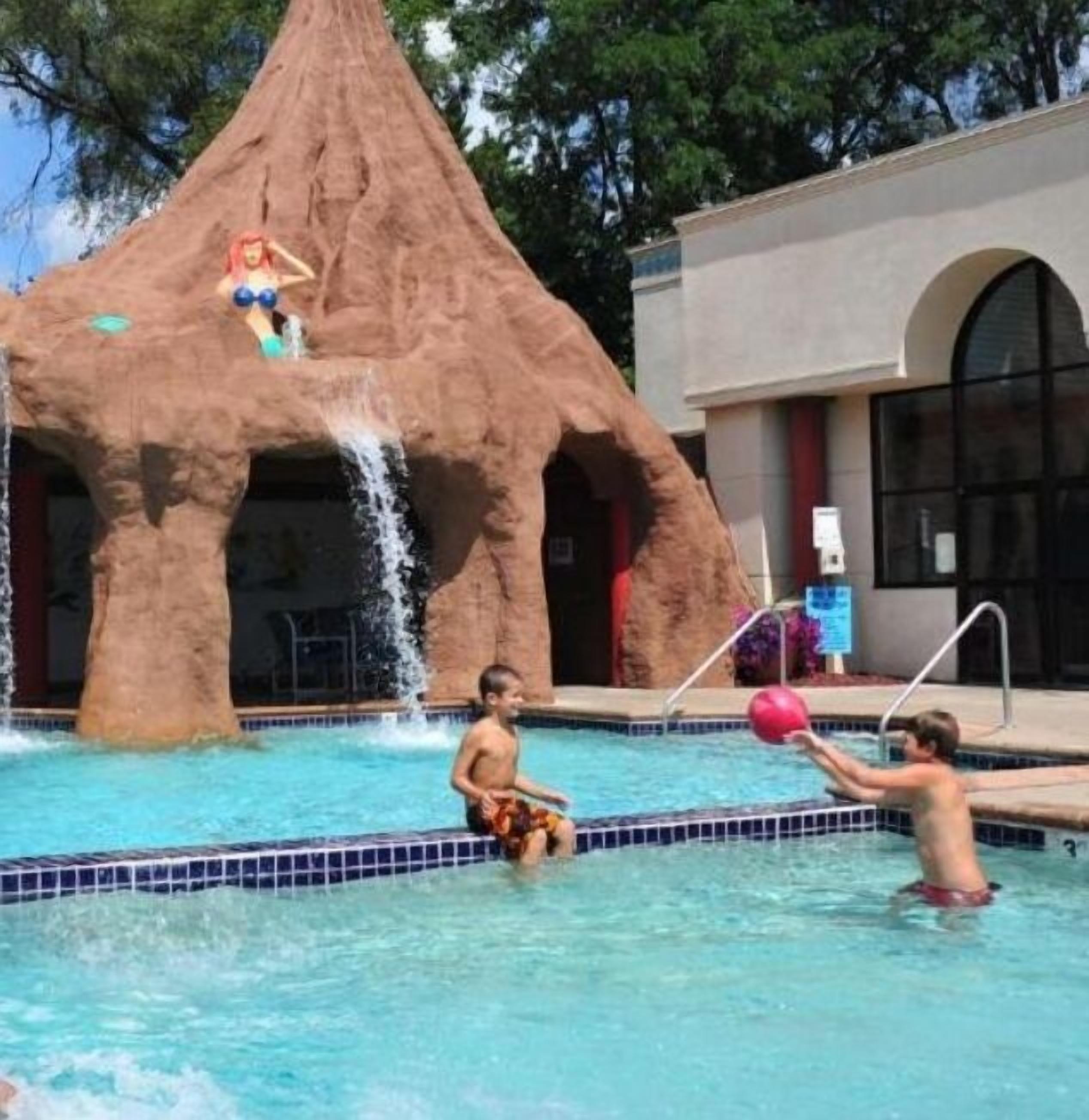 A swimming pool with a rock formation and a water feature.