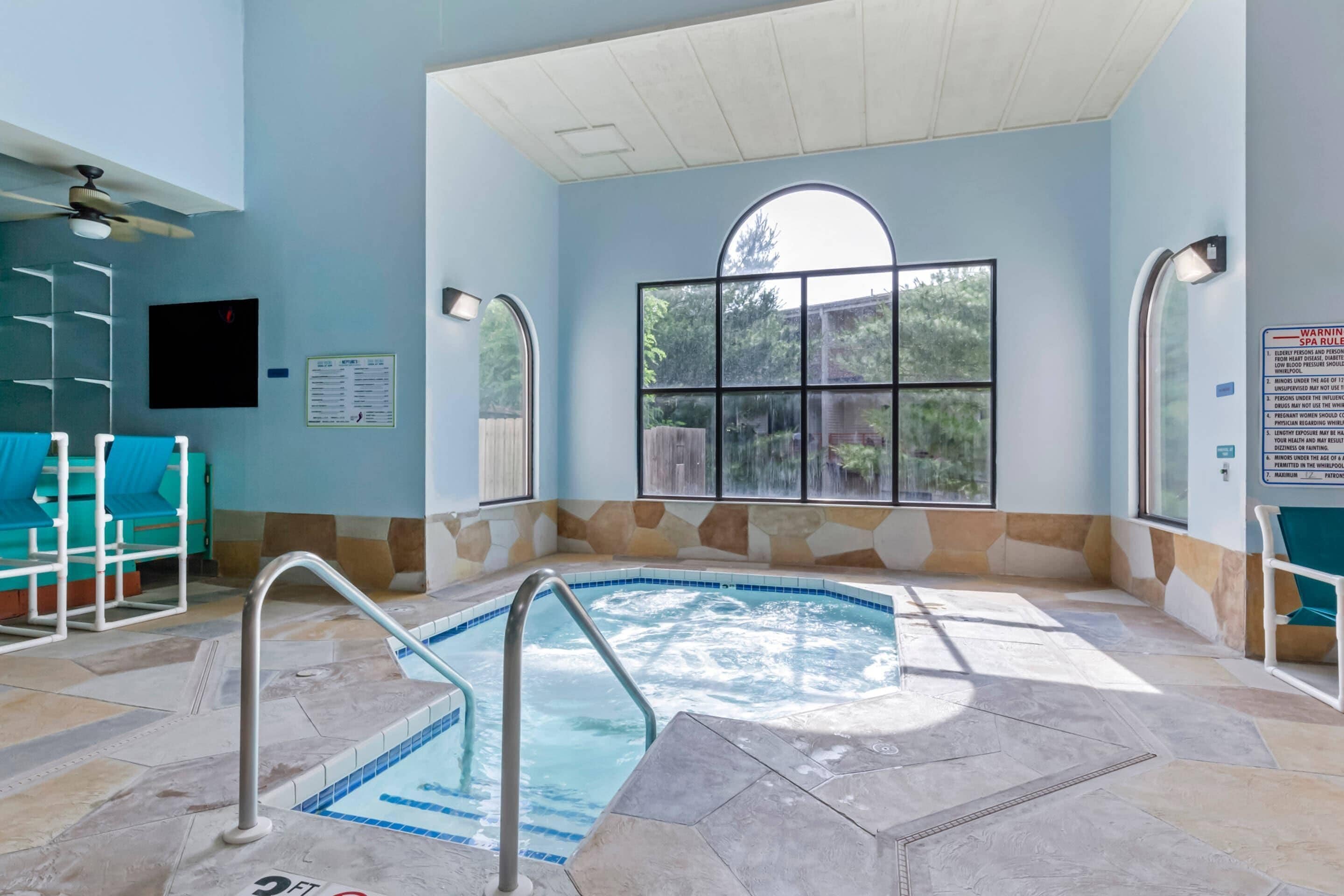 A spa area with a hot tub, seating, and a large window.