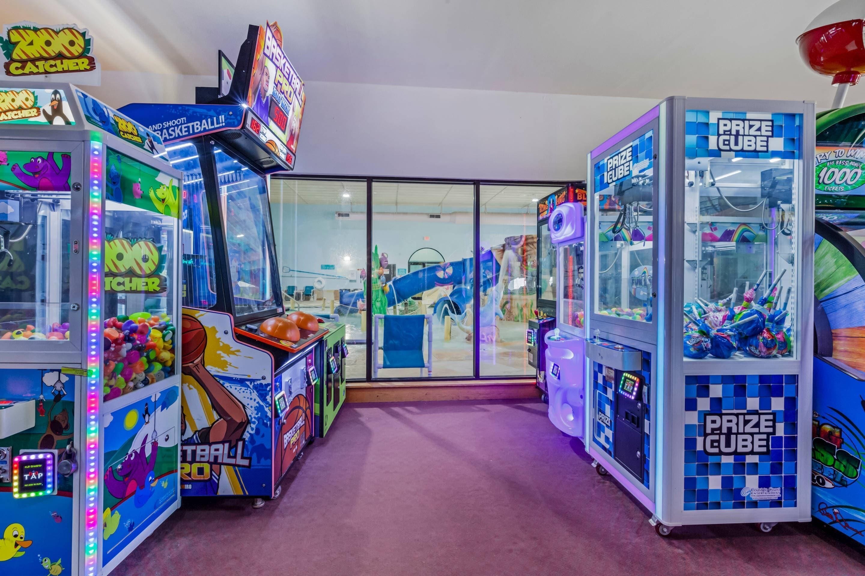 Una fila di luminose macchinette arcade con distributori di premi a cubo, tra cui giochi come '2000 Catcher' e 'Basketball 2000'.