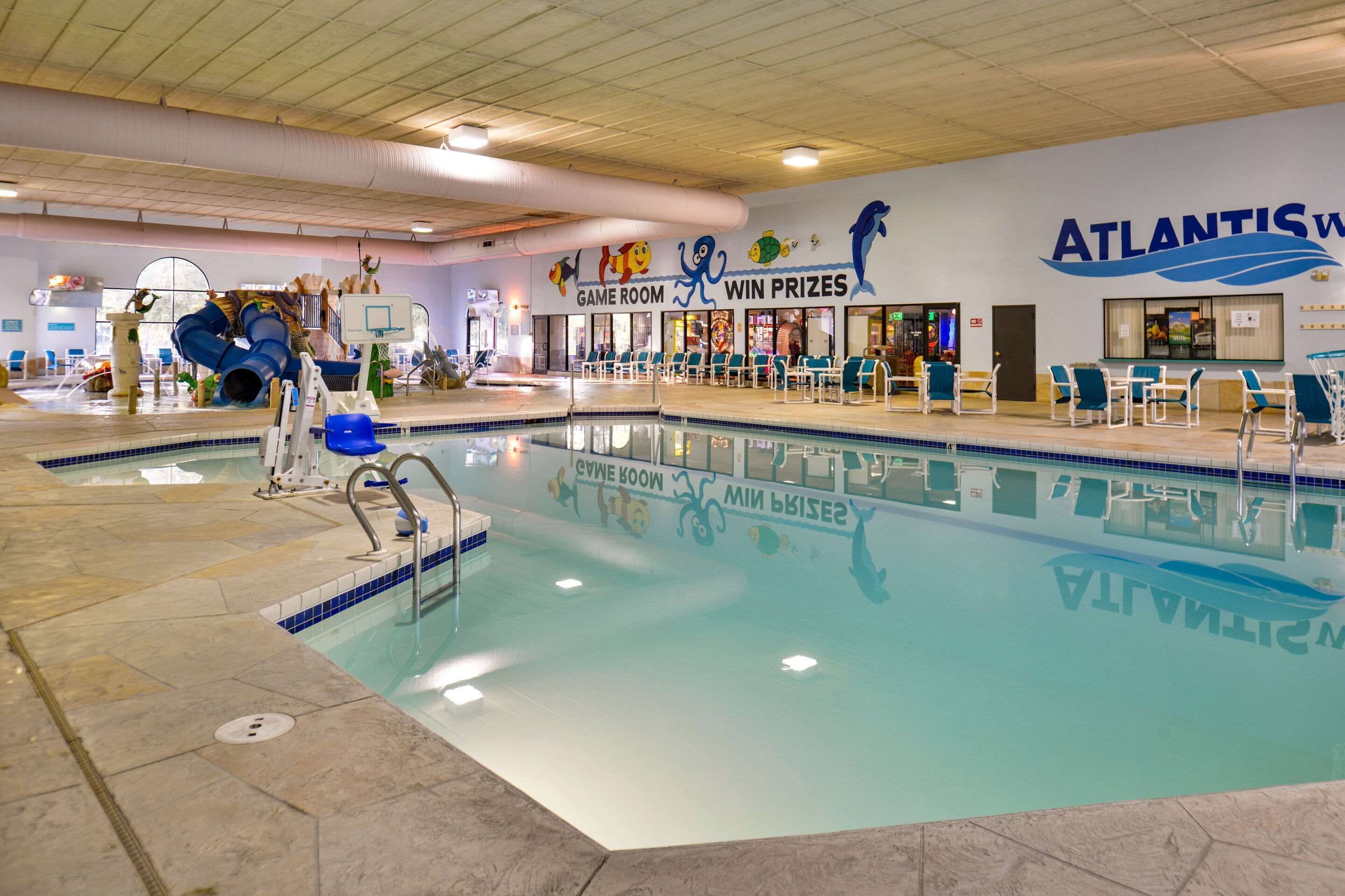 An indoor pool area with a game room and win prizes sign, and a pool with a dolphin mural.