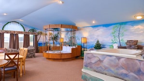 Una habitación con un rincón de estar circular, una bañera y un mural con una escena de playa.