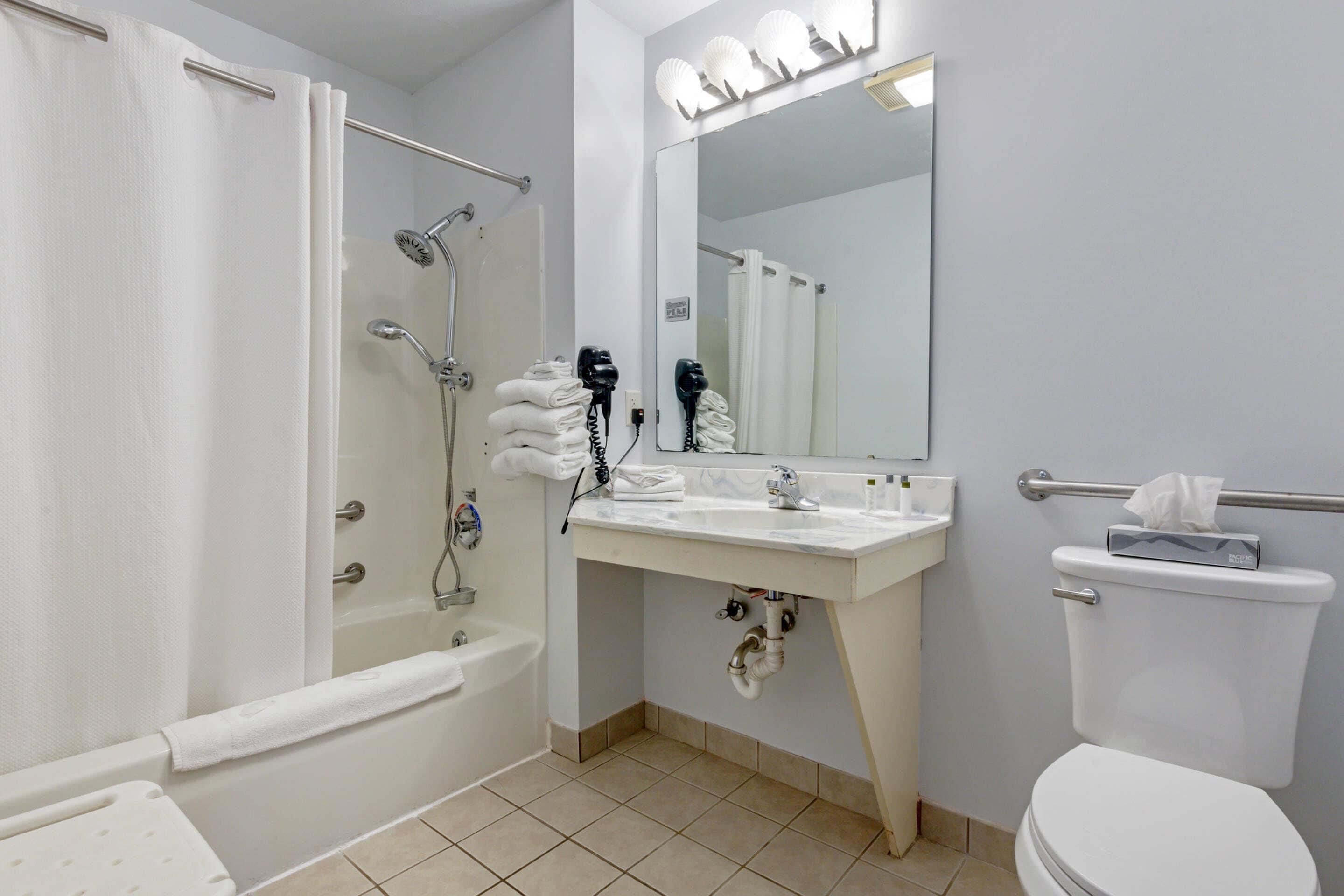 A bathroom with a bathtub, a shower, a toilet, and a vanity with a mirror.