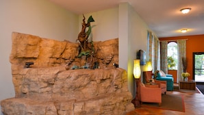 Una sala de estar con una pared de roca, chimenea y un área de descanso con sofá y sillones.