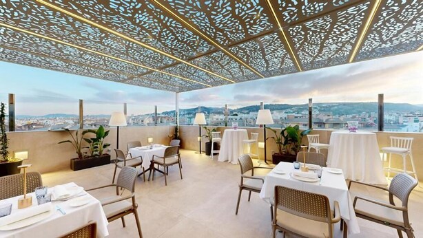 Un espace de restauration en plein air avec des tables et des chaises, un plafond décoratif et une vue sur la ville.
