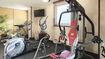 Un gimnasio con equipo cardiovascular, máquinas de pesas y una pantalla de televisión.