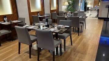 Un espace de restauration d’hôtel comprenant plusieurs tables, des chaises et un écran de télévision.
