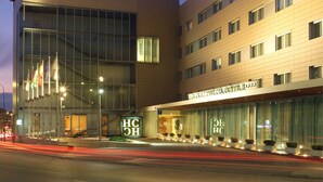 Un hôtel moderne doté d’une façade incurvée, de grandes fenêtres en verre et d’une entrée imposante avec une enseigne lumineuse.