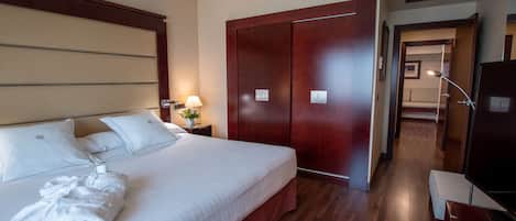 Une chambre d’hôtel avec un grand lit, une armoire en bois, une table de chevet avec une lampe et un téléviseur.