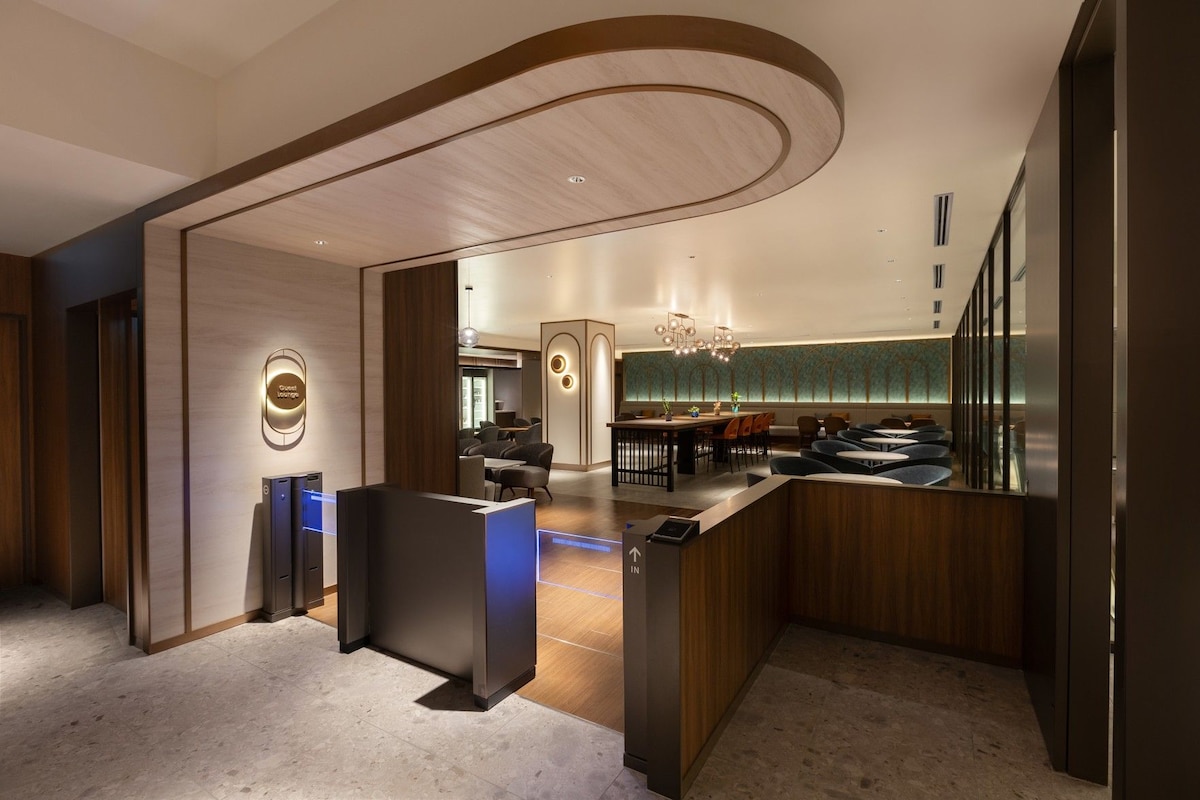 A modern hotel lobby with a reception desk, seating area, and a view of the interior.