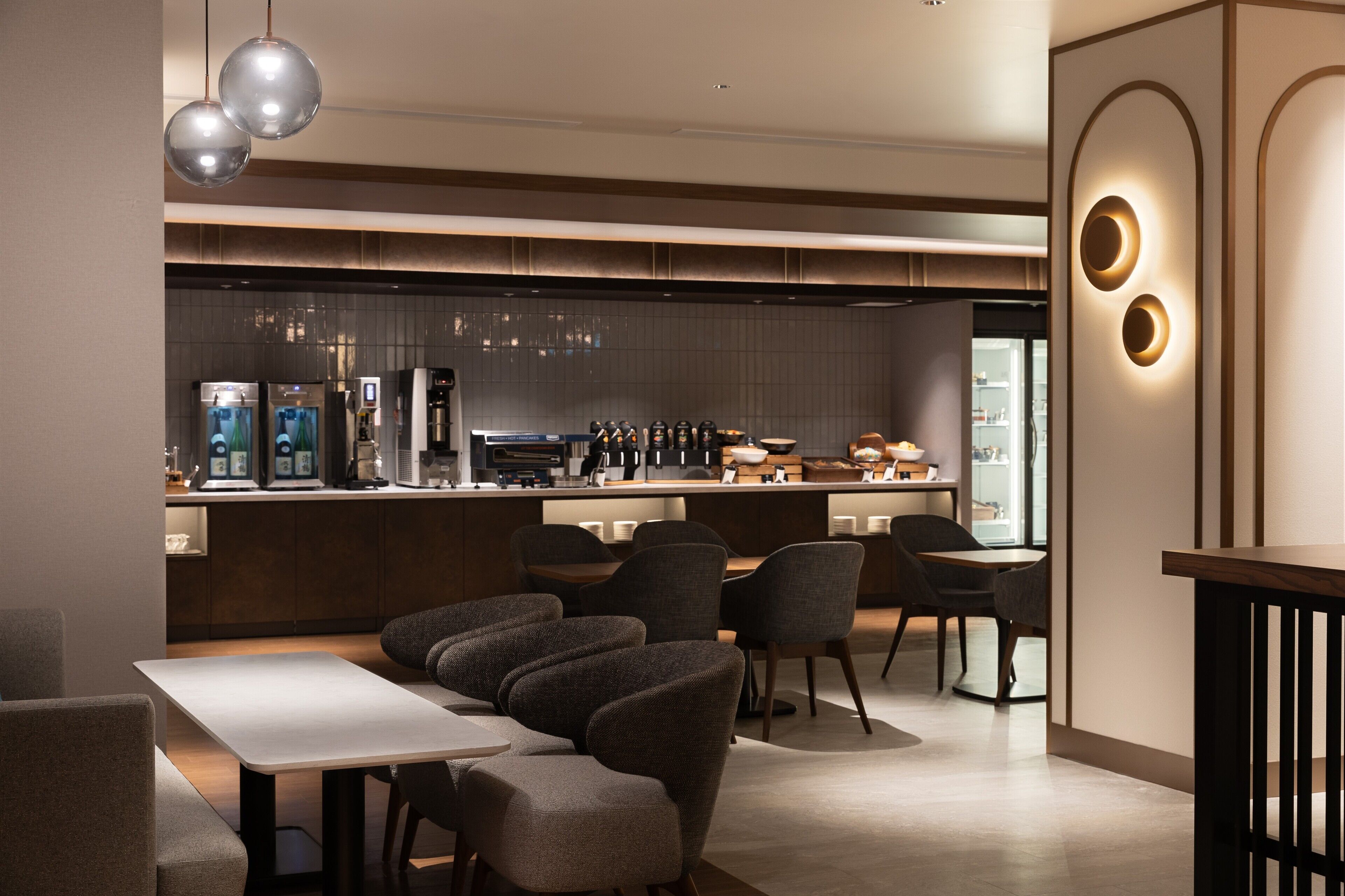 A modern restaurant with a bar area, seating, and a kitchen in the background.