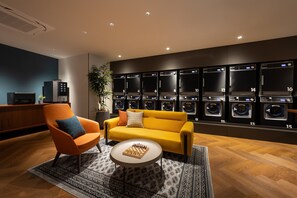 A modern lounge area with a yellow sofa, orange armchair, and a chess table.