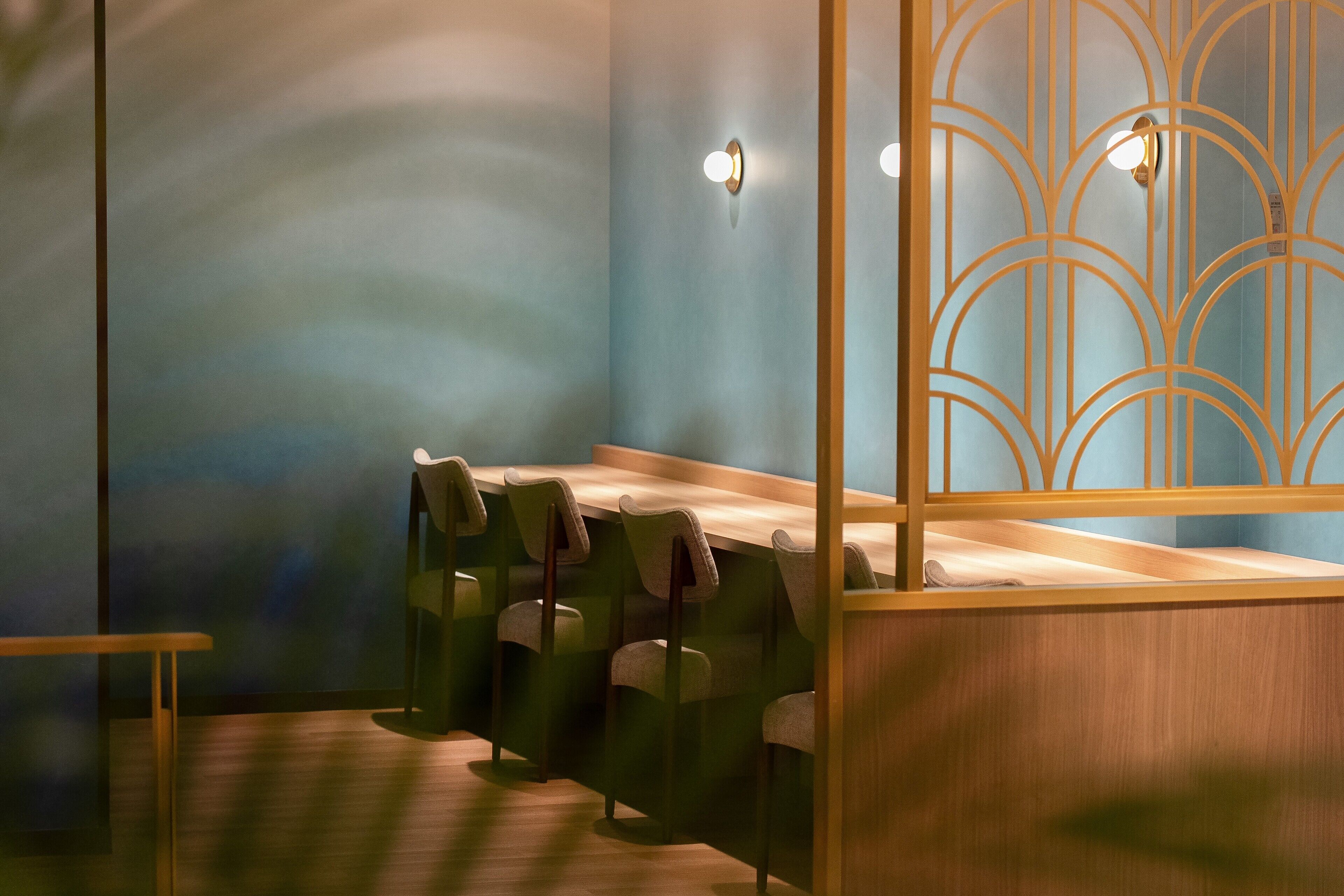 A room with a long wooden table, several chairs, and a decorative partition with light fixtures.