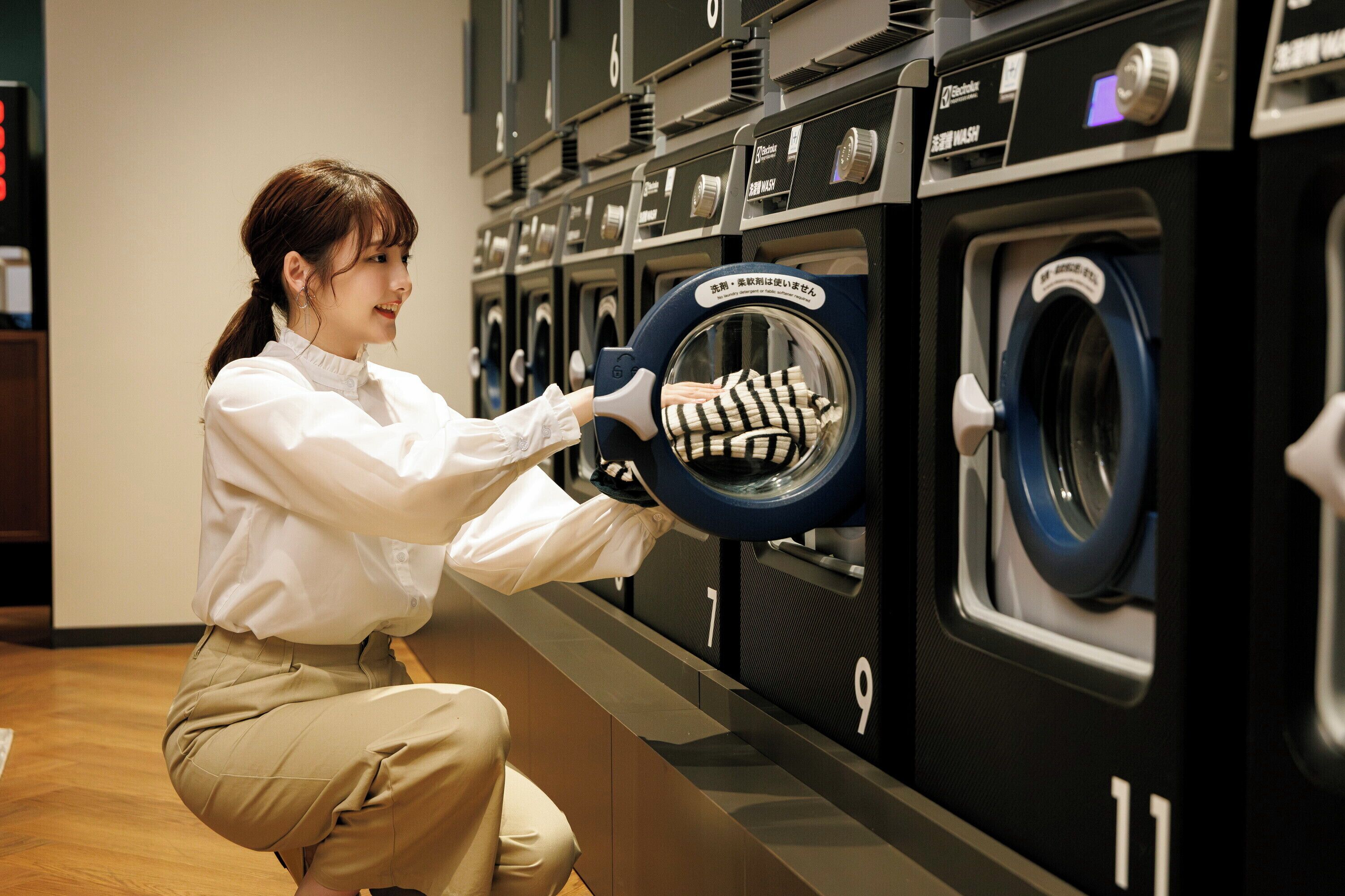 Eine Person bedient eine Waschmaschine mit Frontlader in einer Waschsalon.