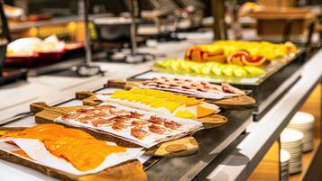 Un bufé con diversos alimentos, incluyendo carnes, quesos y frutas.