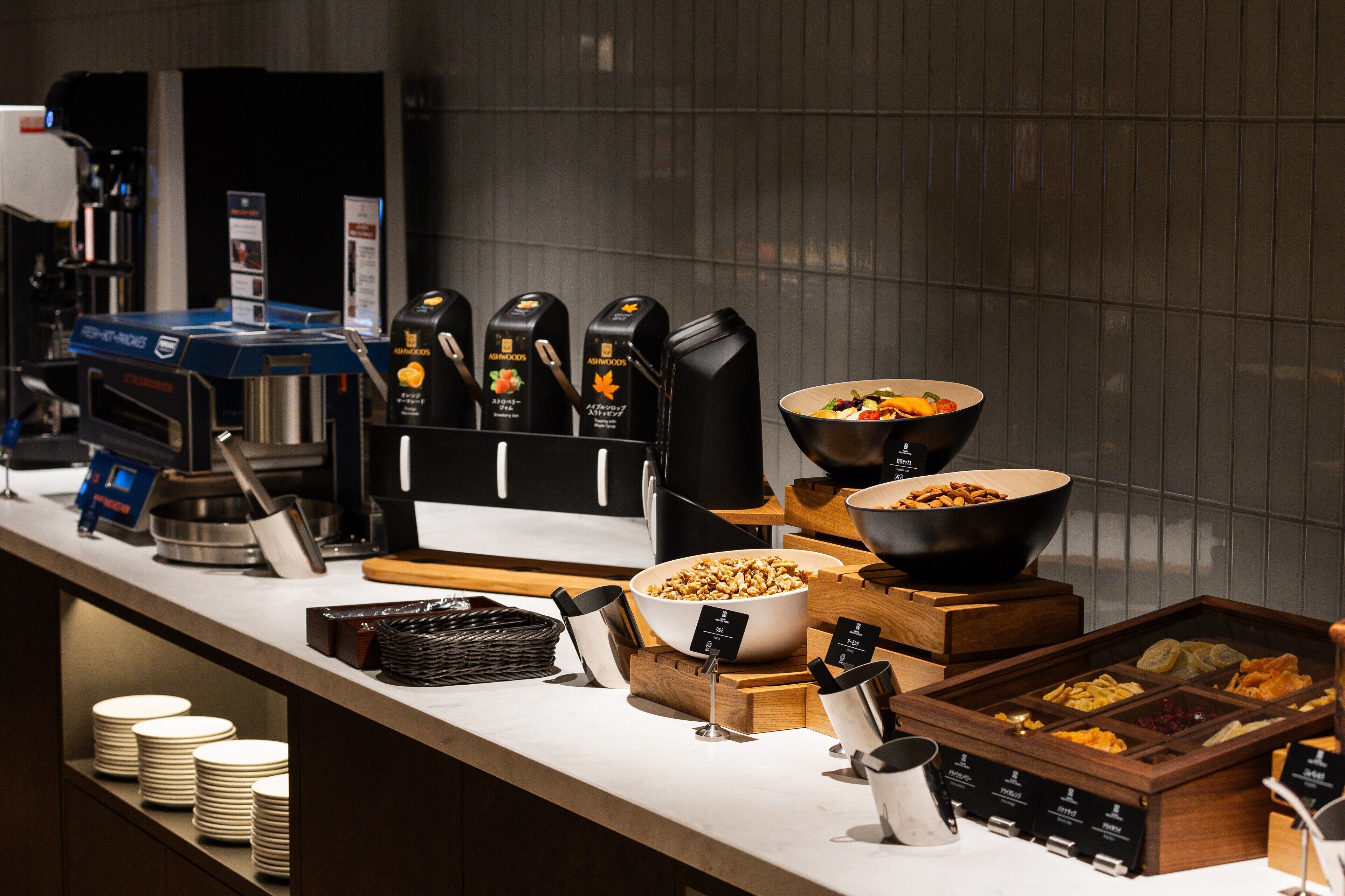 A buffet setup with various food items, coffee machines, and condiment dispensers.