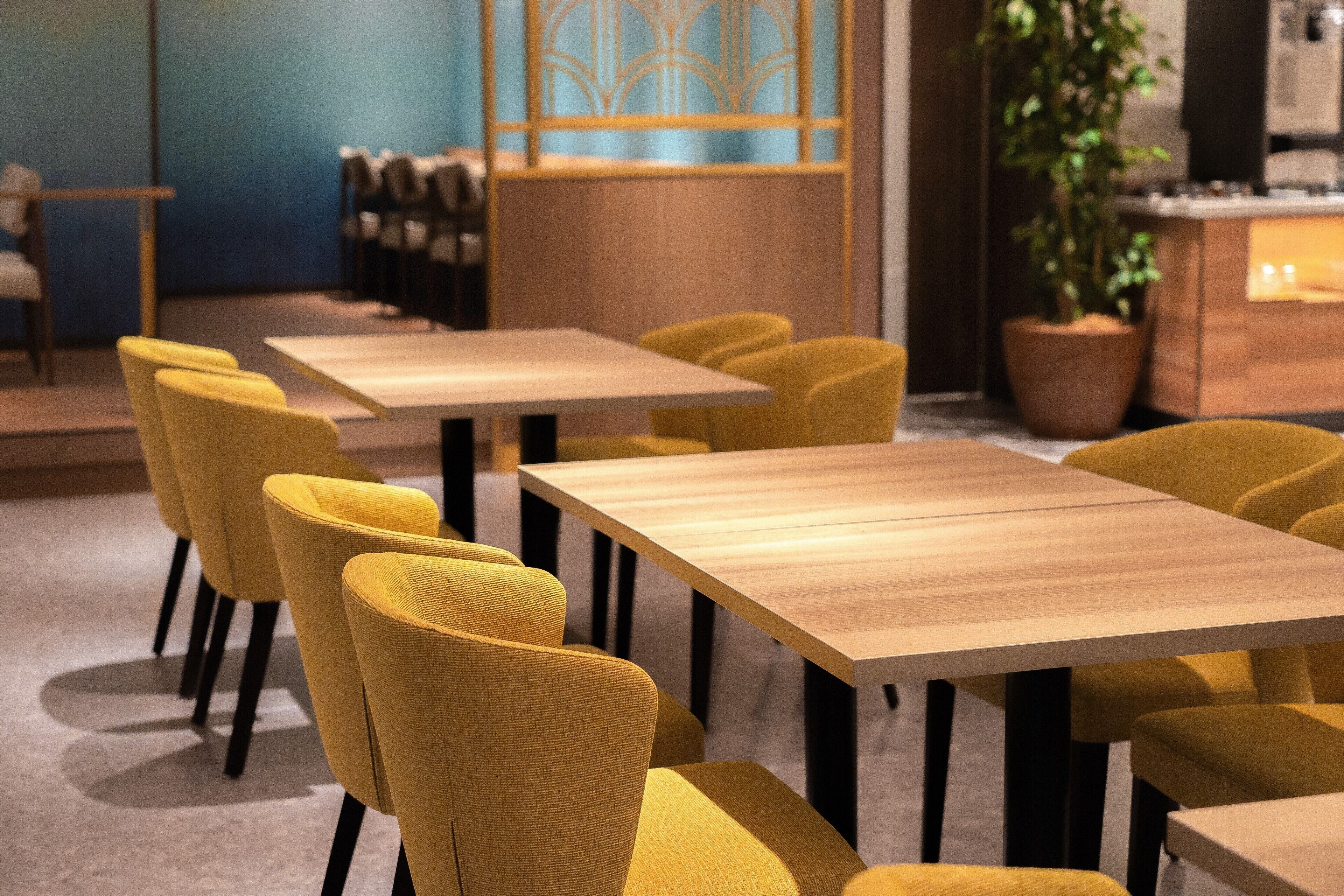A modern dining area with yellow chairs and wooden tables.
