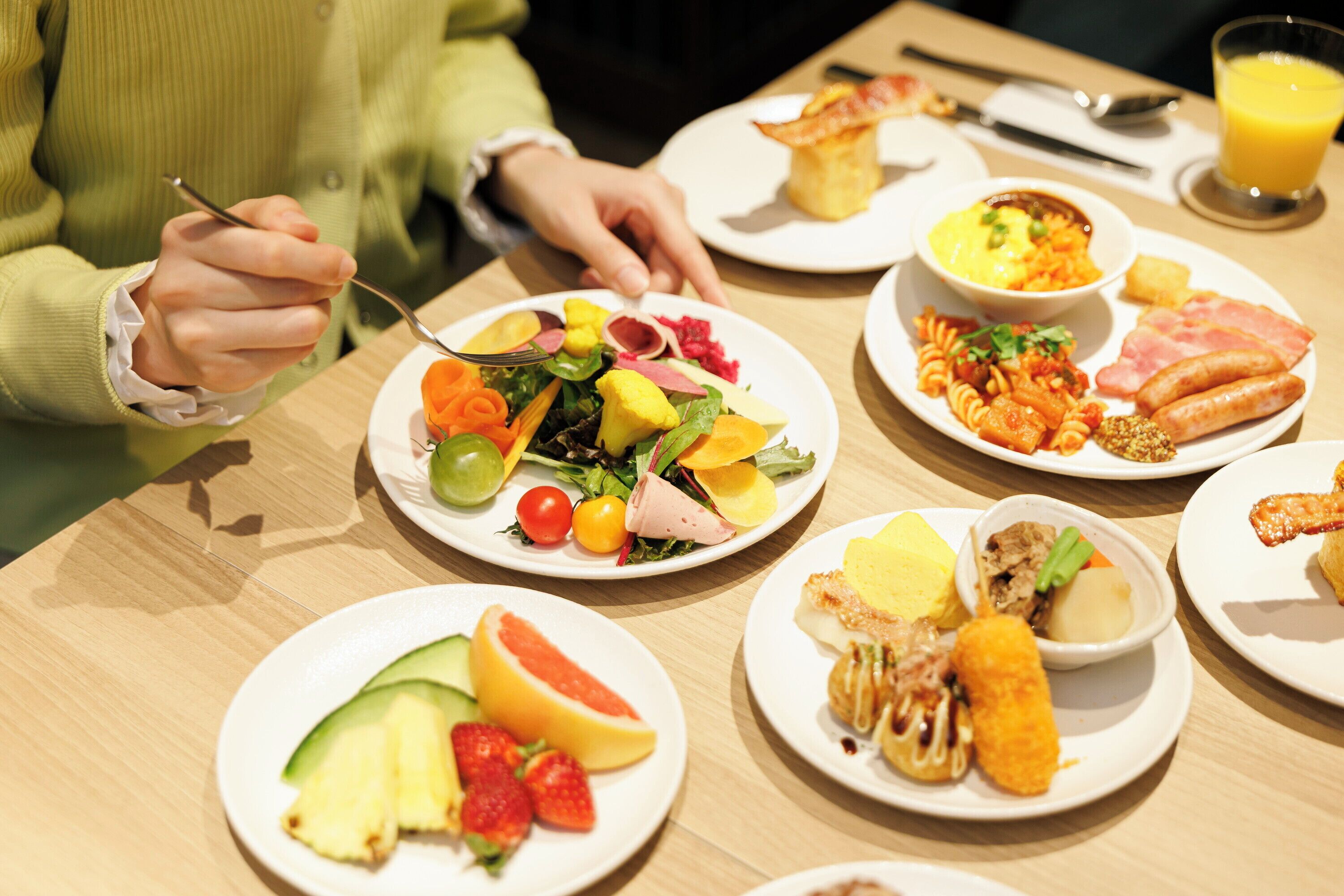 A dining table with various plates of food, including fruits, vegetables, and meats.