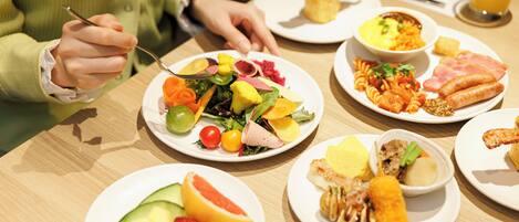 A dining table with various plates of food, including fruits, vegetables, and meats.