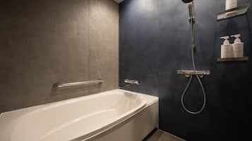 A modern bathroom with a white bathtub, a handheld showerhead, and a wall-mounted shelf with toiletries.