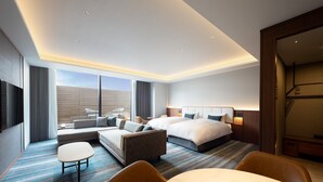 Una habitación de hotel moderna con una cama grande, un sofá, una mesita y una zona de estar.