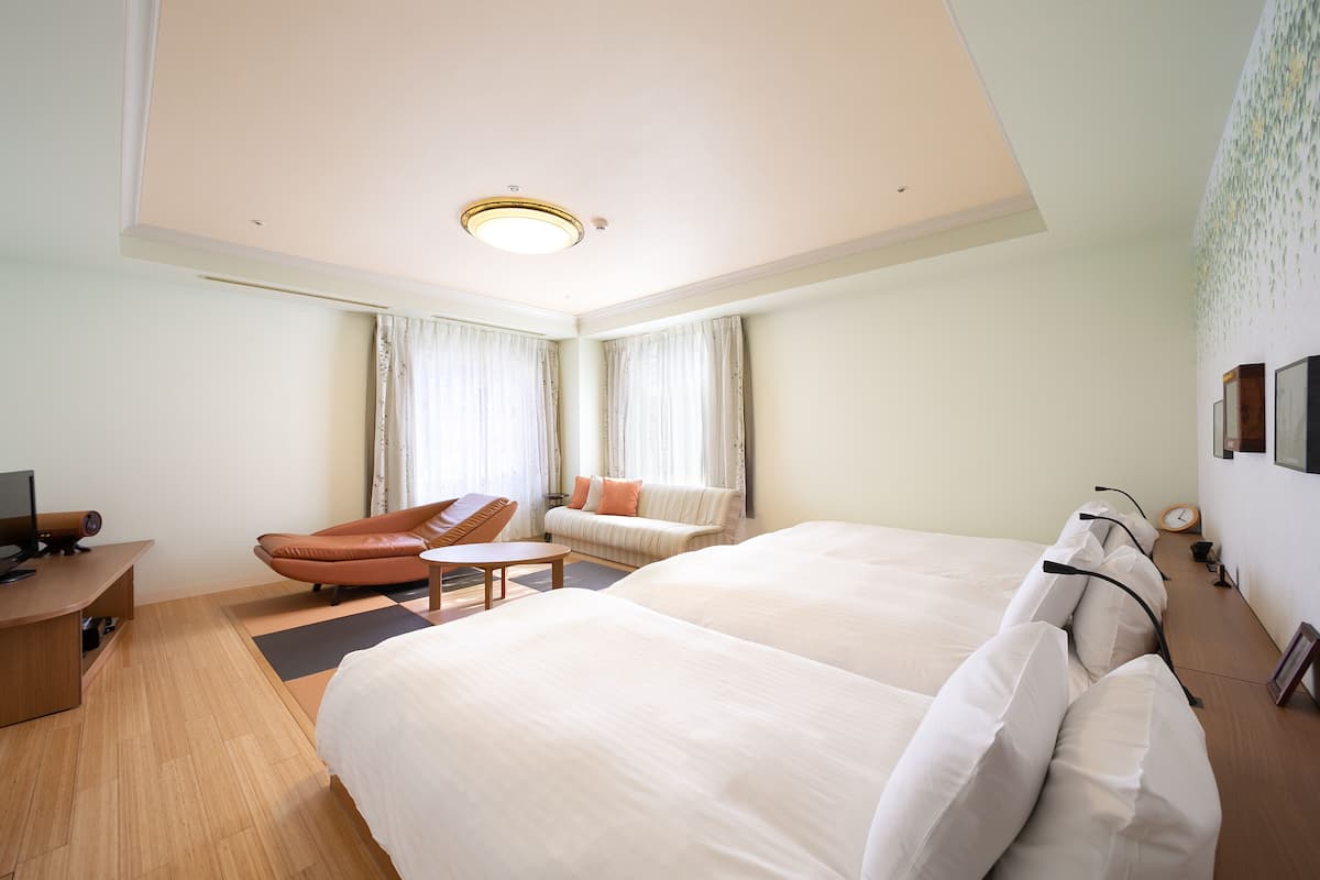 Una habitación de hotel con una cama grande, un sofá, una silla, un escritorio y una lámpara en el techo.