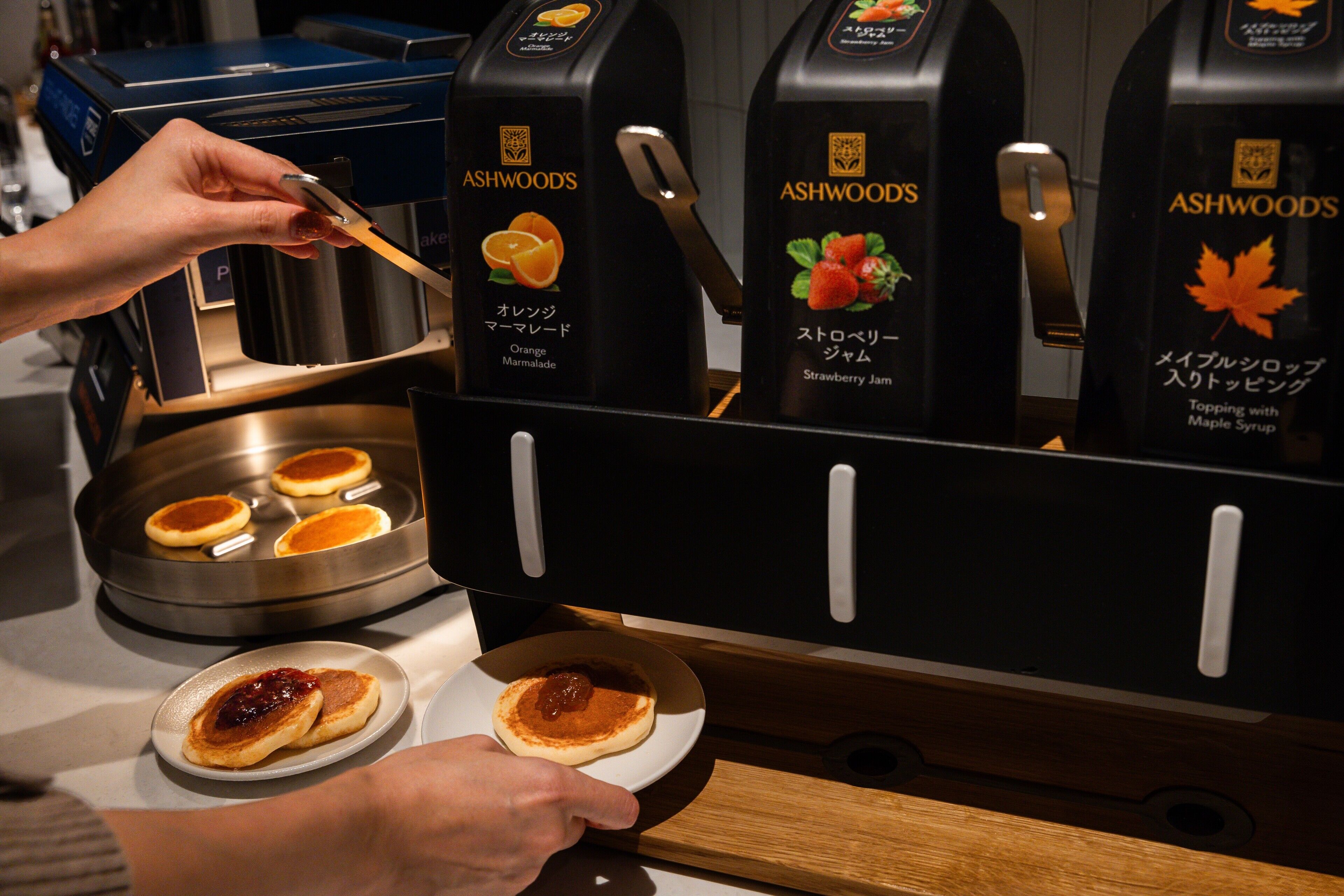 Una cafetera con cuatro tazas de café sobre una bandeja y dos platos con tortitas.
