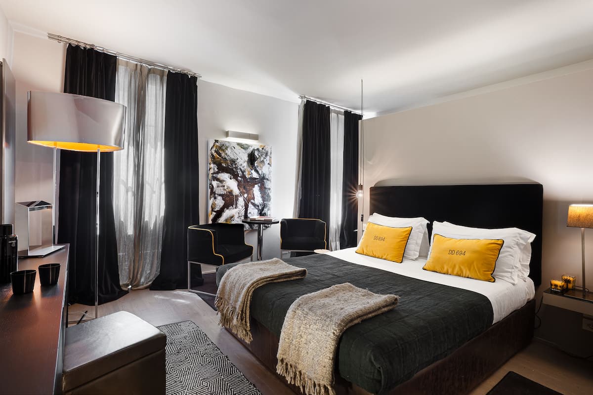 Ein modernes Hotelzimmer mit einem großen Bett, einem Schreibtisch, einem Stuhl und einer Schreibtischlampe.